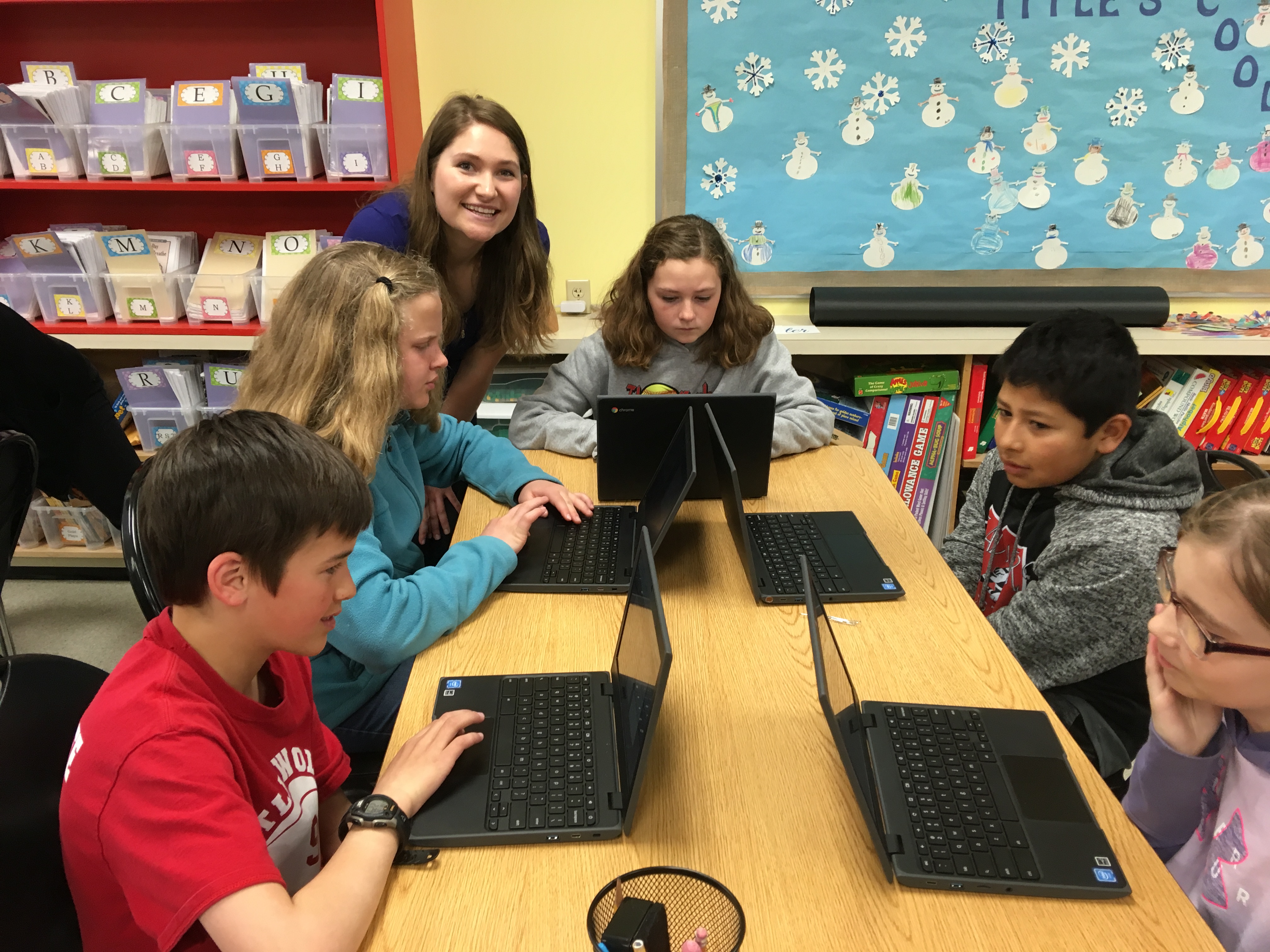 Woman assisting children with a coding exercise