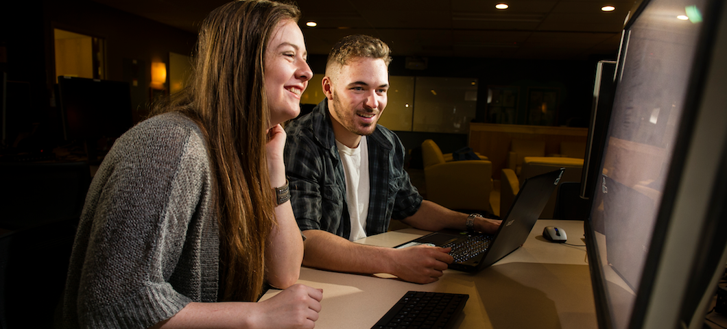 female and male student sitting at computer