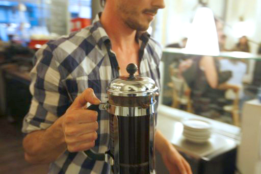 barista with a french press full of coffee